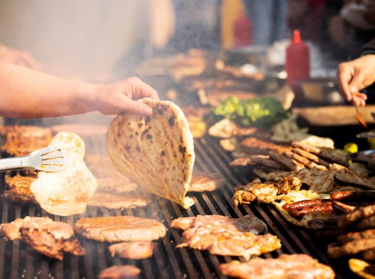 Un uomo gira un panino su piastra ad una sagra